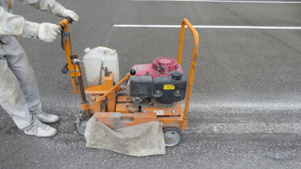 駐車場のレイアウトの変更のため、白線ラインを抹消機で消去する作業工程